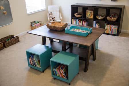 a small rectangular table surrounded by four seating cubes filled with books. An additional low bookcase is in the background.